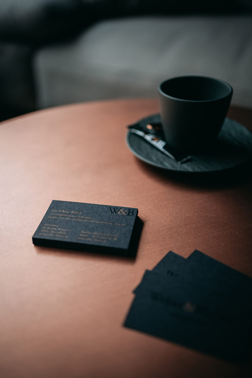 Visitenkarten 1 Zwei Frauen sitzen auf der Couch und schauen sich Exposés in einer Broschüre an.